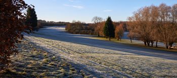 Frozen golf course with golfers This landscape photograph captures a frosty winter morning at Tapton Park in Chesterfield, United Kingdom. The image showcases a frozen golf course where golfers can be seen in the distance, surrounded by a variety of trees that frame the park's natural scenery. The low winter sun casts long shadows across the frost-covered grass, highlighting the seasonal beauty typical of nature in this region. The presence of golf activity and the well-maintained grounds emphasizes Tapton Park's role as a recreational area. Overall, the scene reflects the serene atmosphere of a winter morning in Chesterfield, with frost and trees defining the character of this picturesque park in the United Kingdom.